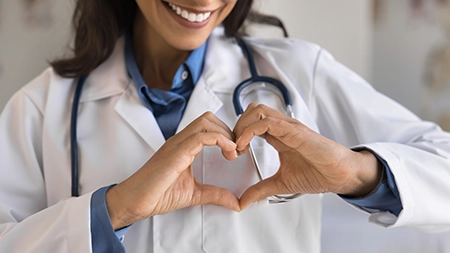 Smiling healthcare professional making heart symbol with her hands