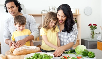 A mother, a father and two children preparing a healthy meal together in a kitchen.