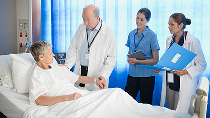 Medical care team addressing a patient in hospital bed