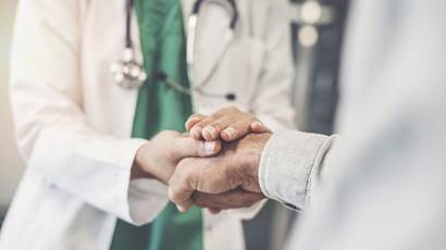 A doctor clasps the hand of a person